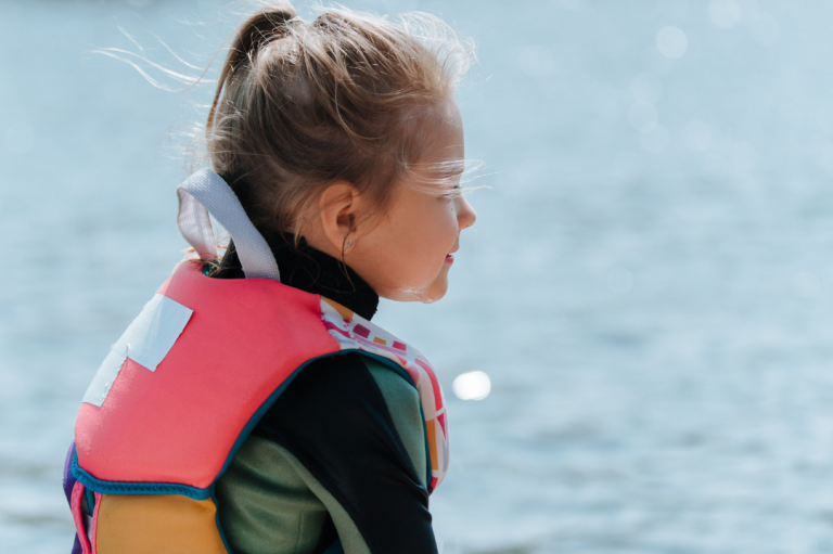 Female Only Event Mädchen mit Rettungsweste blickt nachdenklich auf das Wasser.