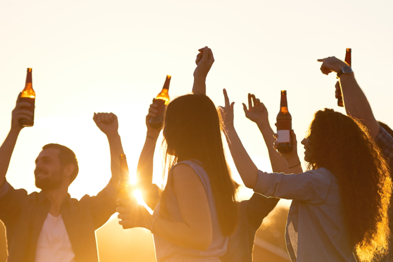 Season Closing Party Gruppe von Menschen feiert bei Sonnenuntergang mit Bierflaschen in der Hand.
