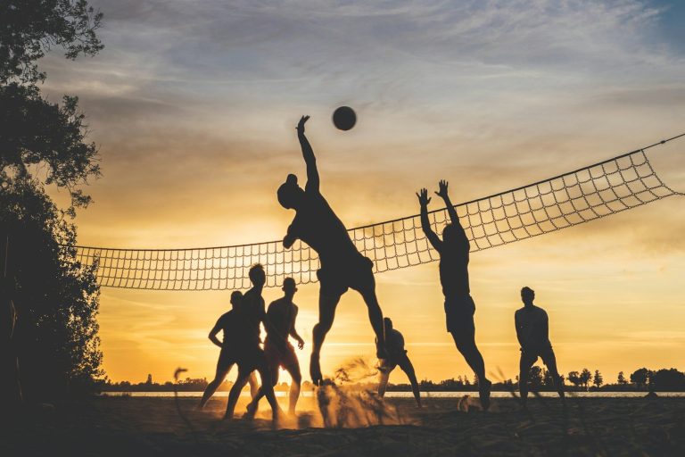 Volleyballturnier Silhouette von Menschen, die am Strand Volleyball spielen, bei Sonnenuntergang.
