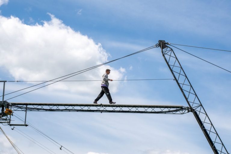 Schier Boards Testtag Ein Mann balanciert auf einem Stahlträger unter einem blauen Himmel mit Wolken.