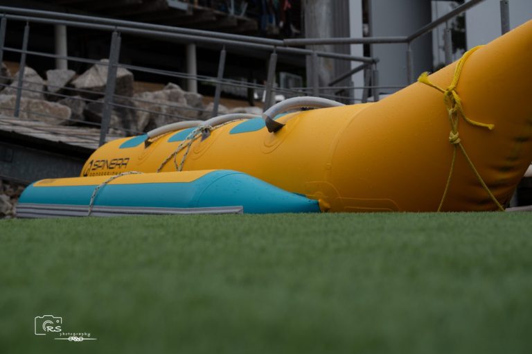 Sommerferien Kick-Off Gelbes Schlauchboot mit blauen Details liegt auf grünem Grasboden.
