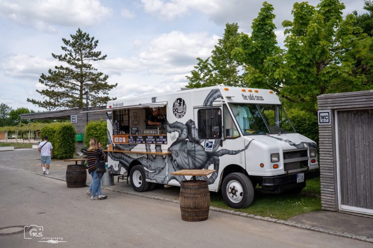 Kostümwettbewerb Ein Food Truck mit einem bunten Design steht an einer Straße, umgeben von Bäumen.