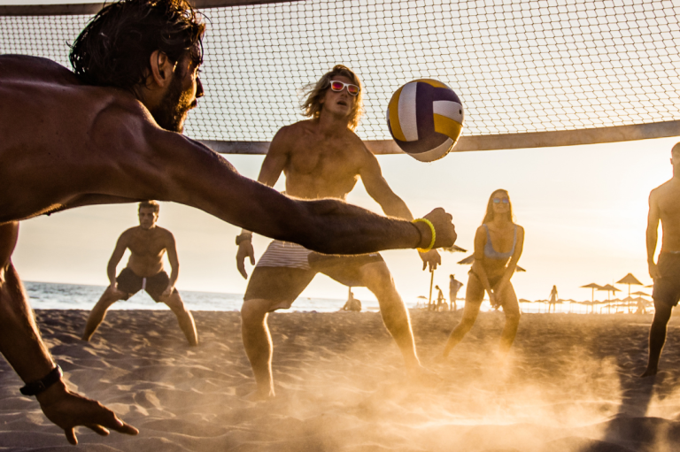 Event "Volleyballturnier" Strand-Volleyballspiel mit mehreren Personen im Sand bei Sonnenuntergang.