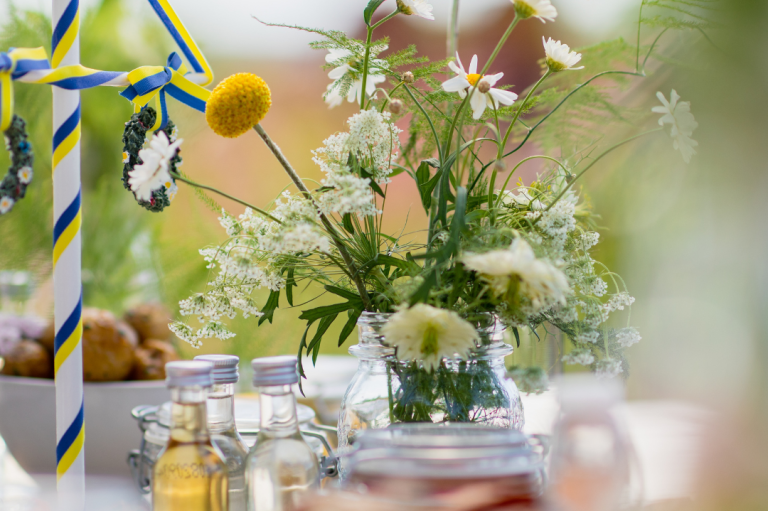Ein Tisch mit Blumenarrangement, Gläsern und dekorativen Elementen in fröhlicher Atmosphäre.