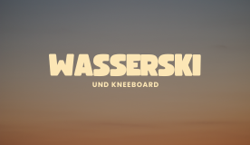 Person beim Wasserskifahren auf einem See, spritzendes Wasser um ihn herum.