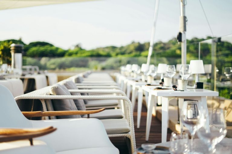 All White Party Elegante Sitzgelegenheiten und gedeckter Tisch in einem Außenbereich mit Blick ins Grüne.
