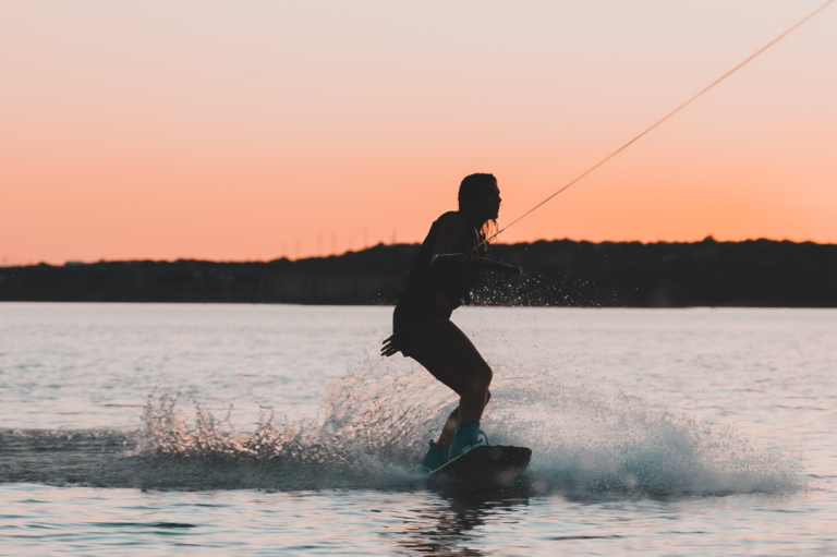 Event "Female Only Event" Mann wakeboardet bei Sonnenuntergang auf ruhigem Wasser.