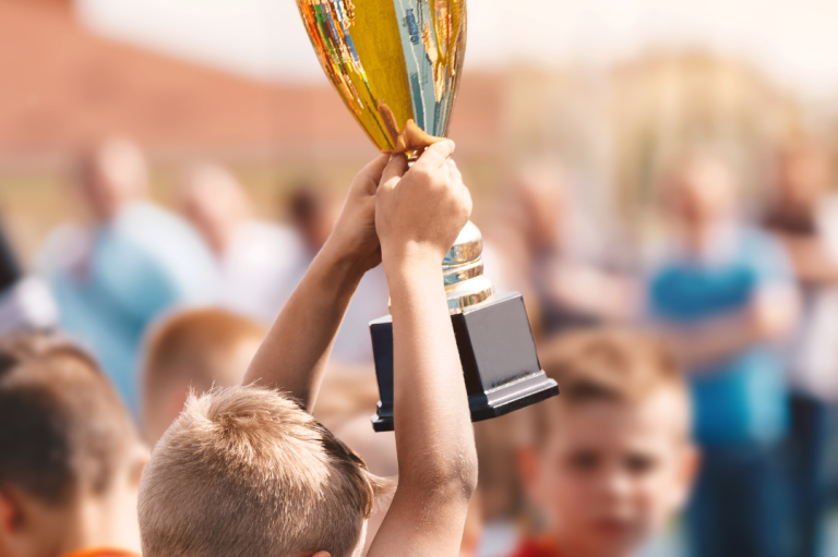 Event "Seifenkistenrennen" Ein Kind hält stolz einen goldenen Pokal über dem Kopf.