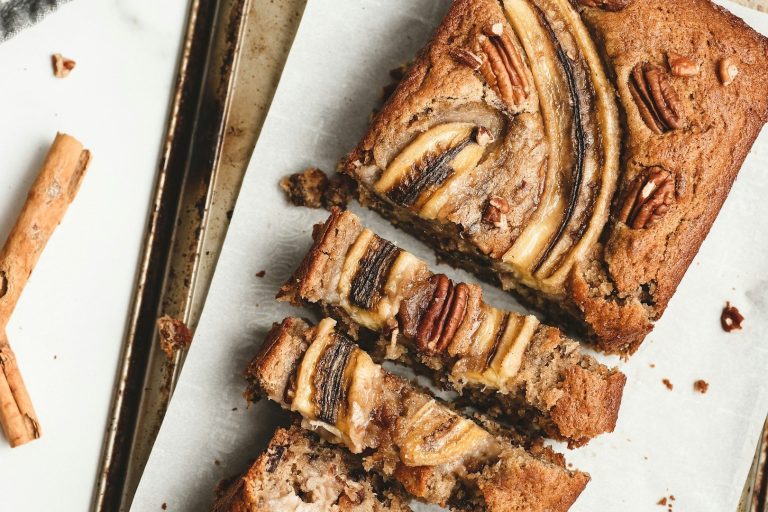 Sportstunde am See Köstlicher Bananenkuchen mit Nüssen, in Stücke geschnitten und auf einem Blech platziert.